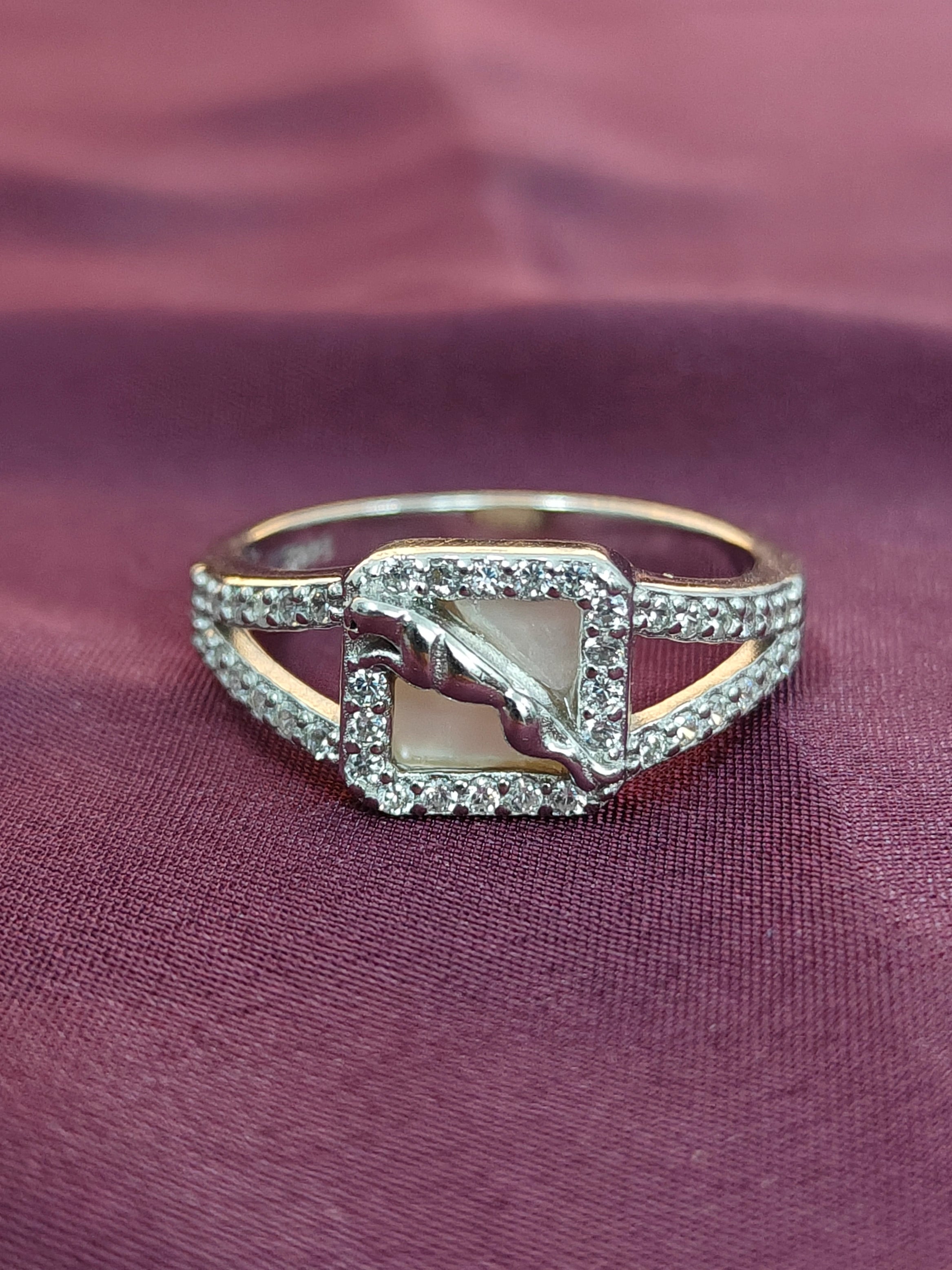 Elegant ring with a central stone and diamond accents on a purple fabric background